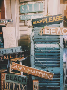 Photo of a rustic blue shutter and beach themed decorative signs.