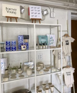 A lightly colored display candles, canvases, soaps, and baby clothes. 