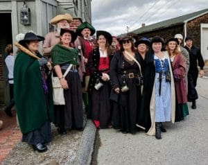 A group of people dressed as pirates stand outside a local pub. 