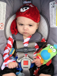 A baby dressed as a pirate with a scowl on his face. 