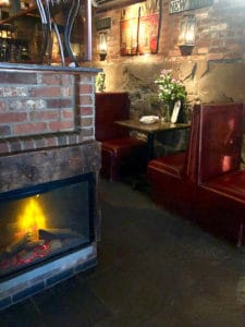 Electric fireplace adjacent to a bank of leather dining booths. 