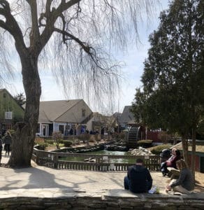 Spring time at the Old Mystic Village as visitors enjoy benches and watch the duck pond