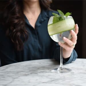 Woman holding gin and tonic with a cucumber and mint leaves in Stonington, CT