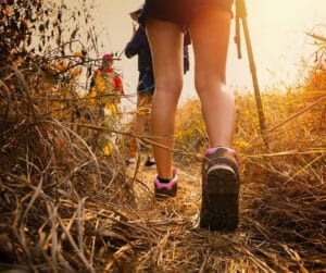 Woman hiking through a path with a walking stick