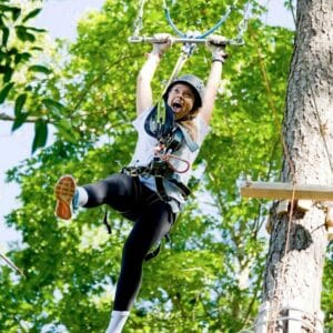 woman zip lining through trees in Mystic, CT, great family friendly spring activity in Mystic