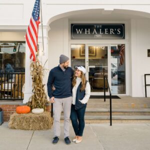 Woman and Man Standing in Front of Whaler's Inn with fall decor in downtown mystic ready to explore the best fall events in Mystic
